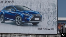 Workers labor near an ad for an SUV at the site of the upcoming Auto Show in Beijing, China, April 20, 2016. 