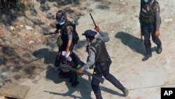 FILE - In this Saturday, March 6, 2021 file photo, police officers hold down a protester as they disperse demonstrators in Tharkata Township on the outskirts of Yangon, Myanmar. The United Nations says after a military takeover of the country, more than 850 people have been kille