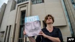 A journalist poses with a portrait of Turkish journalist Ahmet Altan, June 19, 2017, in front of the Istanbul courthouse, where his trial is to take place. 