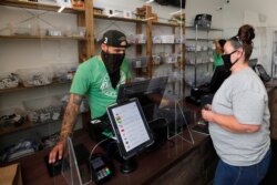 Kerri Thibodeau, of Stoughton, Mass., right, makes a purchase at Pure Oasis, a Black-owned recreational marijuana dispensary, in the Grove Hall neighborhood of Boston, June 24, 2020.