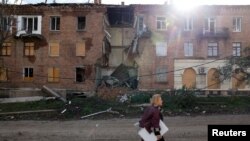 Žena prolazi pored zgrade pogođene u raketnom napadu, dok se nastavlja ruska invazija na Ukrajinu u Bahmutu u Donbasu, 1. novembra 2022. 