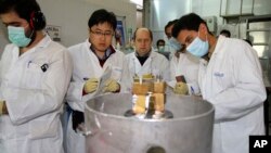 ২০ শতাংশ ইউরেনিয়াম সমৃদ্ধকরণের জন্য জোড়া ক্যাসকেডের মধ্যে থাকা সংযোগ বিচ্ছিন্ন করতে প্রস্তুতি নিচ্ছেন আন্তর্জাতিক পরমাণু শক্তি সংস্থার পরিদর্শক ও ইরানের কারিগররা। নাতানজের কাছে এক পরমাণু গবেষণা কেন্দ্র, ইরান। ফাইল ফটোঃ ২০ জানুয়ারি, ২০২৪।