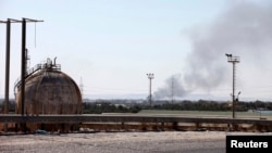 Smoke rises near oil tanks after heavy fighting between rival militias broke out near the airport in Tripoli, July 23, 2014. 