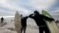 FILE - Surfers bump elbows as they protest against the nationwide lockdown regulations that allow exercise but not water activities, amid the coronavirus disease (COVID-19) outbreak, at Muizenberg beach in Cape Town, South Africa, May 5, 2020.