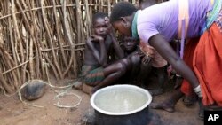 In this photo taken Tuesday, Oct. 17, 2017, a Karamojong woman prepares a meal at her village in the semi-arid savannah region of Karamoja, in northeastern Uganda. (AP/Adelle Kalakouti)