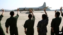 មន្ត្រី​យោធា​​បក់​ដៃ​ដាក់​យន្តហោះ​យោធា​​ជប៉ុន​មួយ​ ខណៈ​ដែល​​យន្តហោះ​​នេះ​ចាក​ចេញ​ពី​មូលដា្ឋន​ទ័ព​អាកាស​ម៉ាឡេស៊ី​​មួយ​មុន​នឹង​ចេញ​ទៅ​ជួយ​រុករក​យន្តហោះ​បាត់ដាន​កាល​ពី​ថ្ងៃ​ទី​២៣ ខែ​មីនា ឆ្នាំ​២០១៤។