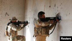 Iraqi security forces take cover during clashes with Islamic State militants, north of Mosul, Iraq, Dec. 30, 2016.