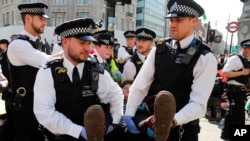 Polisi menangkap para pengunjuk rasa di Oxford Circus di London, Jumat, 19 April 2019. Kelompok Extinction Rebellion menyerukan pekan perlawanan sipil terhadap kegagalan untuk mengatasi penyebab perubahan iklim.
