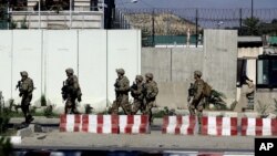 U.S. military forces stand guard at the site of a suicide attack near a U.S. military camp in Kabul, Afghanistan, Sept. 16, 2014.