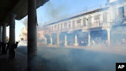 Polisi anti huru-hara Irak menembakkan gas air mata sambil memblokir Jalan al-Rashid saat bentrok dengan demonstran di Baghdad, Irak, 17 November 2019.