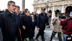 A tourist pushes her floating luggage in a flooded St. Mark's Square, in Venice, Italy, Nov. 13, 2019. 