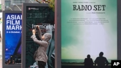 A man takes pictures in front of movie posters during the Busan International Film Festival at Busan Cinema Center in Busan, South Korea, Oct. 1, 2015. 