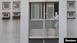 FILE - A medical staff member is seen by a window at the Jinyintan hospital, where the patients with pneumonia caused by the new strain of coronavirus are being treated, in Wuhan, Hubei province, China, Jan. 20, 2020.