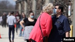 Pasangan berciuman sambil mengenakan masker di Milwaukee, Wisconsin, AS, 7 April 2020. (Foto: Reuters)