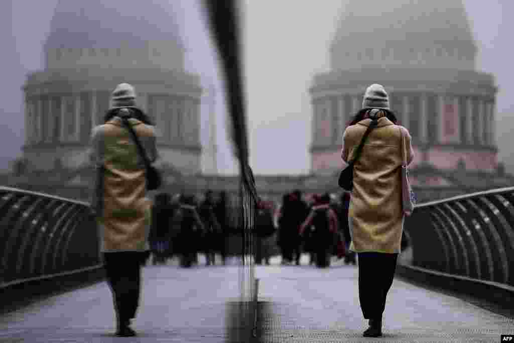 Pedestrians cross the Millennium Bridge during foggy weather in London.