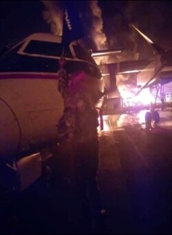 An image distributed by al Shabaab after the attack on a military base in Kenya shows a Somalia's al Shabaab militant holding the group's flag next to a burning aircraft, said to be at the Manda Bay Airfield in Manda, Lamu, Kenya January 5, 2020. Al…