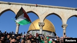 Para peziarah memegang bendera Palestina seusai shalat Jumat di kompleks yang dikenal Muslim sebagai Haram al-Sharif dan orang Yahudi menyebutnya sebagai Temple Mount/Bukit Kenisah di Kota Tua Yerusalem, di saat warga Palestina menyerukan "hari kemarahan" sebagai tanggapan atas pernyataan Presiden AS Donald Trump, yang mengakui Yerusalem sebagai ibukota Israel, 8 Desember 2017. 