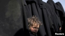 A boy waits with his mother as they queue with others for humanitarian and medical help in Deir Al Zor, Syria, March 5, 2019. 