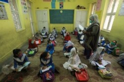 FILE - Students wear protective face masks, maintaining a safe distance as they attend a class amid COVID-19 pandemic in Peshawar, Pakistan, Sept. 30, 2020.