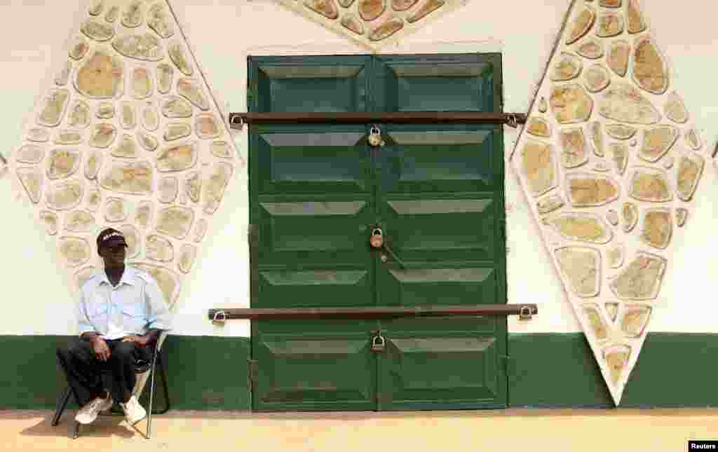 2012年12月31日，一名保安坐在班吉一家关门的店铺边。