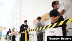 People queue to receive a dose of the Pfizer BioNTech vaccine at the Central Middlesex Hospital in London, Aug. 1, 2021.
