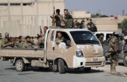 Turkey-backed Syrian rebel fighters sit in a truck near the border town of Tal Abyad, Syria, Oct. 22, 2019.