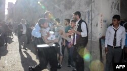 FILE - A man carries an injured child after four rockets fired from Syria slammed into the southern Turkish town of Kilis, killing four Syrians — including three children — in the latest deadly cross-border strike to panic residents, April 18, 2016.