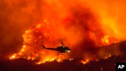 Sebuah helikopter berusaja memadamkan kebakaran hutan di Yucaipa, California, Sabtu (5/9). 