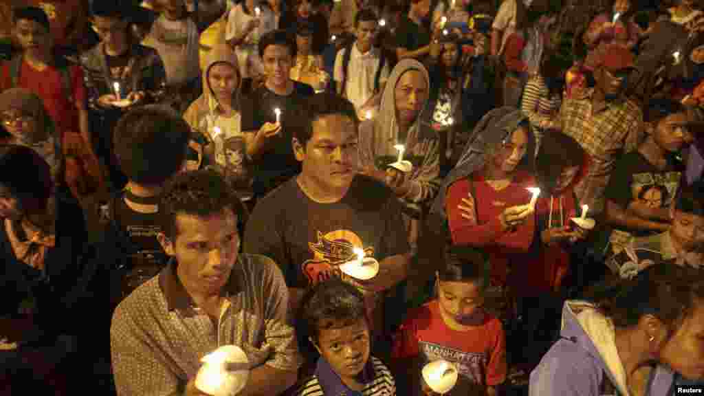 Indonesians hold up candles during a candle light vigil for the victims of AirAsia Flight 8501 at Surabaya, Dec. 31, 2014. 