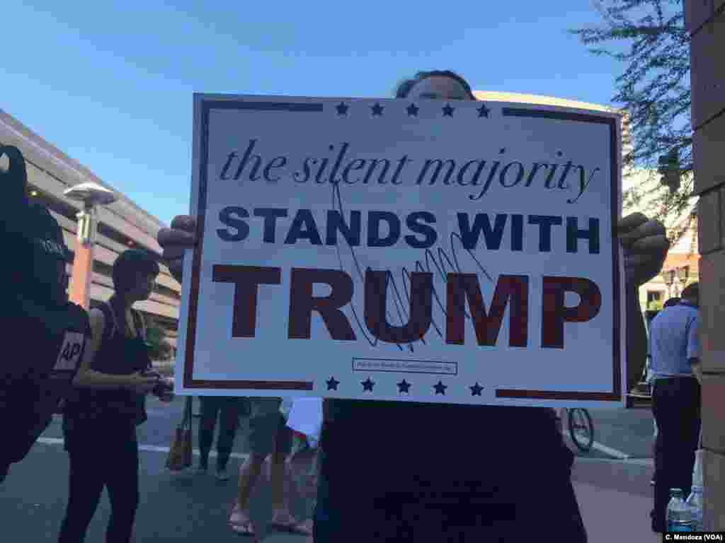 A pro Trump supporter displays a sign that President Donald Trump signed. She told protesters they were wrong in demonstrating against Trump, in Phoenix, Aug. 22, 2017.