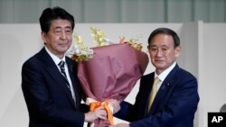 14일 일본 자민당 총재로 당선된 스가 요시히로 관방장관이 아베 신조 총리로부터 축하 꽃다발을 받고 있다.
