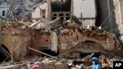 Citizens ride their scooters and motorcycles by a house that was destroyed in Tuesday's massive explosion in the seaport of Beirut, Lebanon, Aug. 5, 2020. 