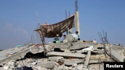 Palestinian children sit atop the remains of their house, which witnesses said was destroyed in the Israeli offensive, during a 72-hour truce in Khan Younis, southern Gaza Strip, Aug. 13, 2014. 