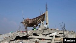 FILE - Palestinian children sit atop the remains of their house, which witnesses said was destroyed in the Israeli offensive, during a 72-hour truce in Khan Younis, southern Gaza Strip.