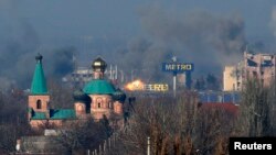 Asap tampak di terminal tua, kiri, dan sebuah gedung di bandara setelah tembakan artileri dalam pertempuran antara separatis pro-Rusia dan pemerintah Ukraina di Donetsk, Ukraina timur, Minggu (9/11).