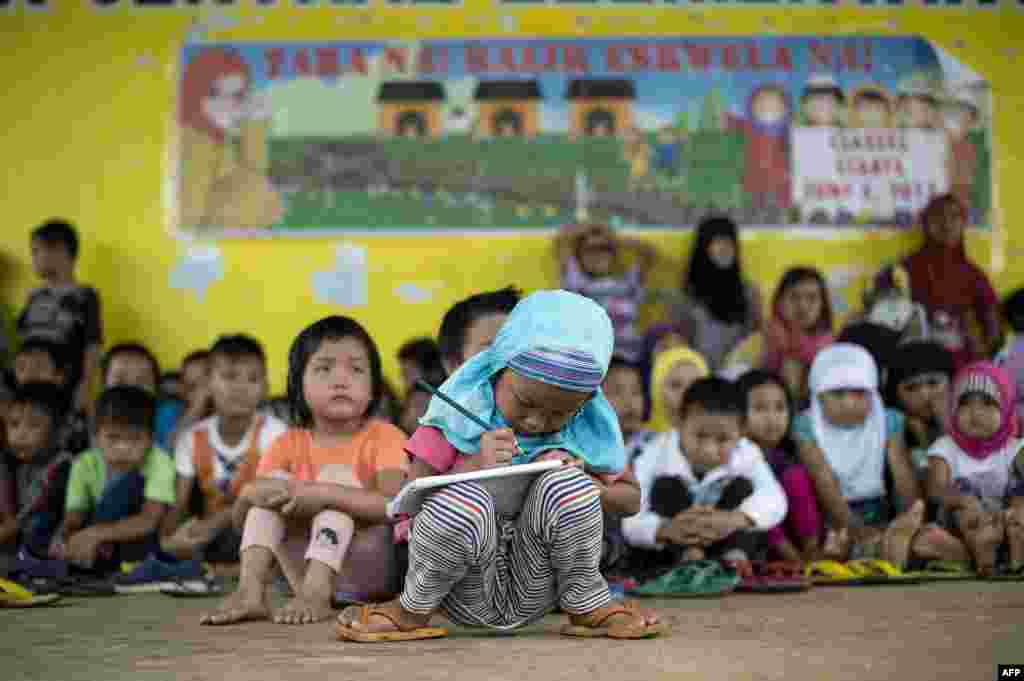 Johainah Nasrodeng, 5, writes in her notebook at a makeshift classroom at the Pantar Central Elementary School in Pantar, Lanao del Norte on the southern island of Mindanao, Philippines.&nbsp; The schoolchildren, some 238 of them with their parents fled by foot for eight hours from Marawi City to Pantar municipality to escape heavy fighting between the government troops and Islamists militants.