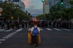A demonstrator kneels in front of a Police line in Downtown Los Angeles on May 30, 2020 during a protest against the death of George Floyd.