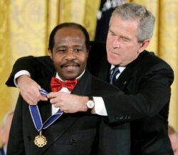FILE - U.S. President George W. Bush presents a Presidential Medal of Freedom to Paul Rusesabagina, who sheltered people at a hotel he managed during the 1994 Rwandan genocide, at a ceremony at the White House in Washington, Nov. 9, 2005.