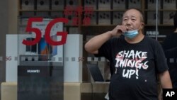 រូបឯកសារ៖ បុរស​ជនជាតិ​ចិន​ម្នាក់ កំពុង​ឈរ​នៅ​ក្បែរ​ហាង Huawei ដែល​ផ្សព្វផ្សាយ​សេវាកម្ម 5G នៅ​ទីក្រុង​ប៉េកាំង កាលពី​ថ្ងៃពុធ ទី២២ ខែកក្កដា ឆ្នាំ២០២០។