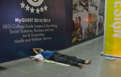 A man sleeps on a sidewalk in Kuala Lumpur, Malaysia. (Z. Peter/VOA)