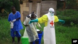 FILE - A health worker sprays disinfectant on his colleague after working at an Ebola treatment centre in Beni, Eastern Congo.