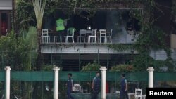 ប៉ូលិសកំពុងត្រួតពិនិត្តទីតាំងក្រៅភោជនីយដ្ឋាន O'Kitchen និង ហាងនំបុ័ង Holey Artisan Bakery នៅថ្ងៃ០៣ កក្កដា។