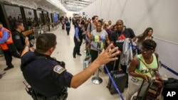 Des officiers de police surveillent la file d'attente du terminal 7 à l'aéroport de Los Angeles, le 28 août 2016.
