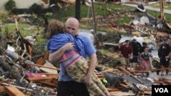 Seorang lelaki menyelamatkan seorang anak perempuan yang terkurung di bawah reruntuhan rumahnya yang dirobohkan tornado di Joplin, Missouri (23/5).