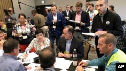 FILE - David Stern (Top-R), a cyber security official with the Department of Homeland Security, works with Colorado county elections officials at a security training exercise in Denver, Sept. 6, 2018.