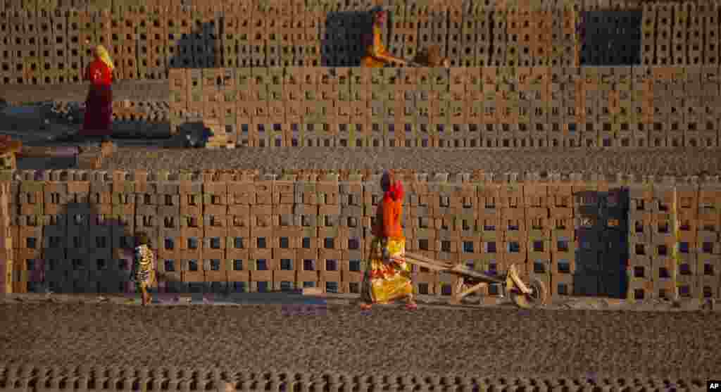 Para pekerja perempuan memindahkan batu bata dengan menggunakan kereta yang ditarik tangan di pinggiran kota Jammu, India.