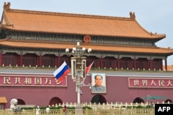 Russia's national flag flies beside the Chinese flag in front of Tiananmen Gate next to Tiananmen Square during the state visit of Russian President Vladimir Putin in Beijing on May 16, 2024.