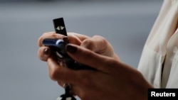 Seorang perempuan menggunakan rokok elektrik buatan Juul di New York, 27 September 2018.