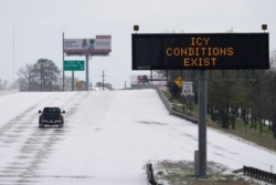 A truck drives past a highway sign on Feb. 15, 2021, in Houston. A frigid blast of weather across the U.S. plunged Texas into an unusually icy emergency Monday that knocked out power to more than 2 million people.