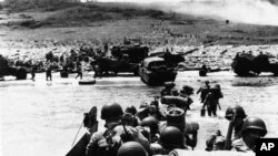 Kamioni-amfibije i pripadnici pešadije izlaze na obalu na početku invazije na Francusku, 6. juna 1944. 